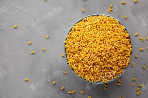 Preview: Dry Organic Pasta Coquillettes in a Bowl, top view. Flat lay, overhead, from above. Copy space.