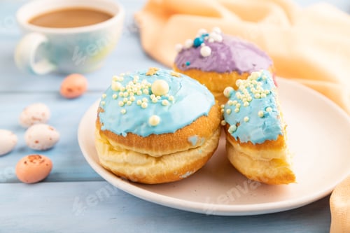 Preview: Purple and blue glazed donut and cup of coffee on blue wooden, side view, selective focus.