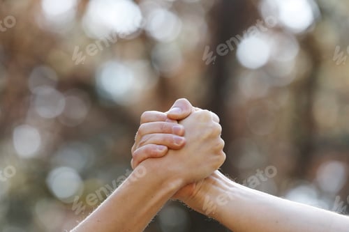 Preview: two people shaking hands isolated on a natural background in the park. isolate two hands holding on