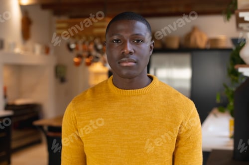 Preview: Portrait of african american man standing in kitchen at home looking straight to camera