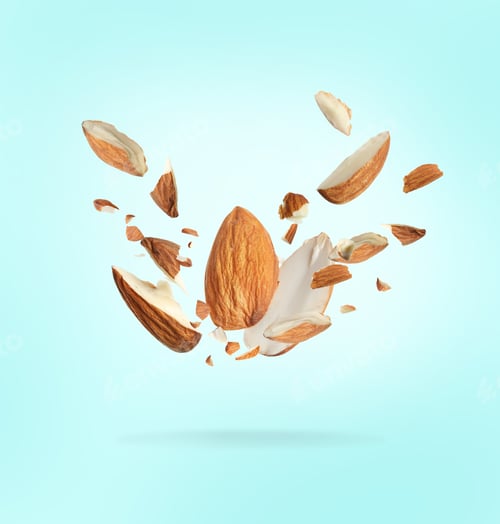 Preview: Pieces of tasty almonds falling on light blue background