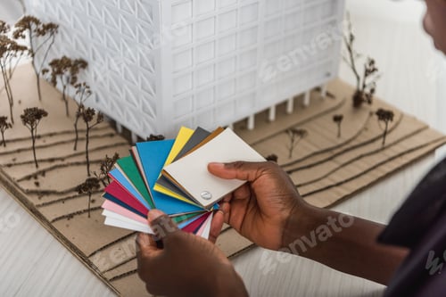 Preview: cropped view of african american adult female architect holding color palettes and working on