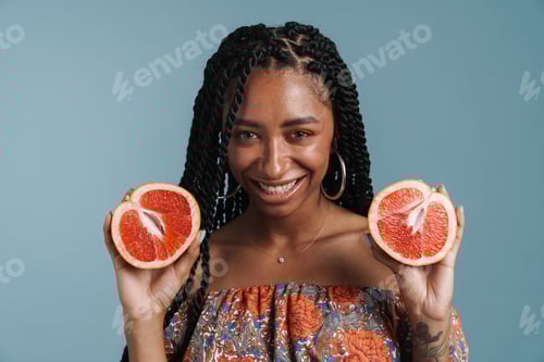 Preview: Young black woman with makeup laughing while showing grapefruit