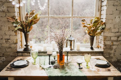 Preview: Beautiful vintage dining table with decorations, flowers, candles and laying near the window.