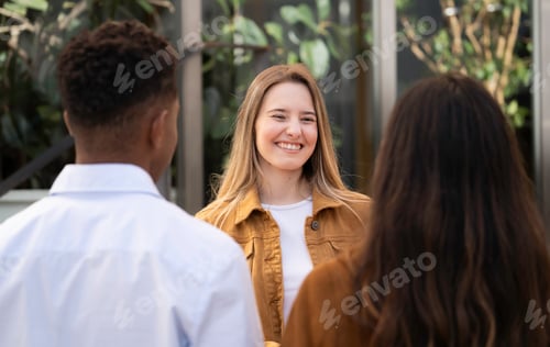 Preview: Young smiling student woman smiling and talking with friends outdoors