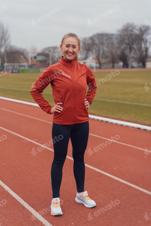 Preview: Portrait of young fitness woman running at a track and field stadium