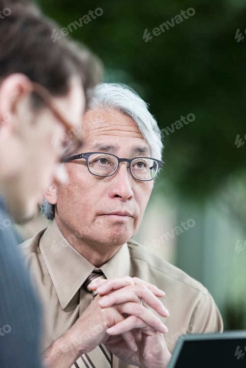 Preview: An Asian businessman and Caucasian businessman working on lapt top computer