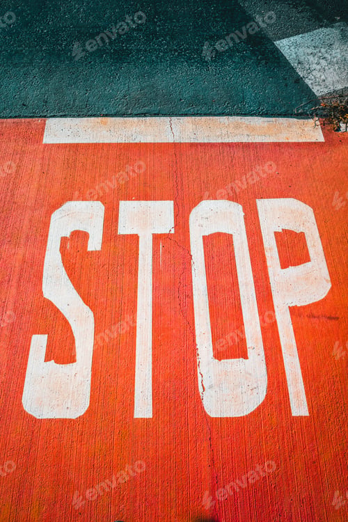 Preview: A stop sign painted on the rough red concrete floor, vertical copy space.