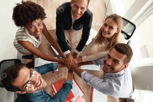 Preview: Top view of business people holding hands together and looking at camera with smile while