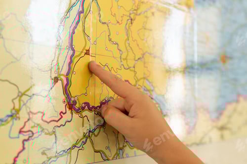 Preview: Close-up of Caucasian boy pointing his finger on world map in a classroom at elementary school