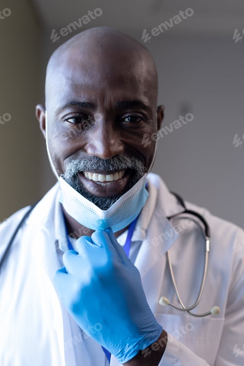 Preview: Portrait of smiling african american male doctor in hospital with face mask