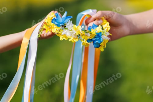 Preview: Close-up on Ukrainian wreath with flowers and ribbons in hands of children hope for end of war
