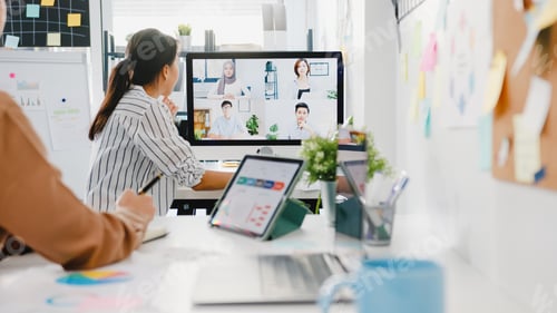 Preview: Asia businesspeople using desktop talk to colleagues in video call meeting in office.