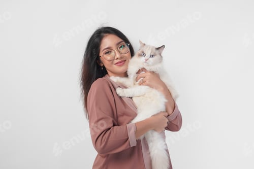 Preview: Lovely Asian woman wearing eyeglasses holding her ragdoll cat and smiling to the camera.