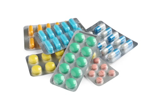 Preview: Pile of different pills in blister packs on white background