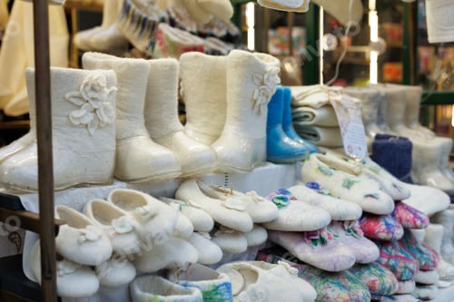 Preview: Handcrafted felt boots and slippers arranged on a display for sale.