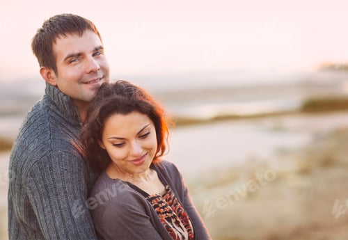 Preview: Portrait of young happy couple laughing in a cold day by the autumn sea