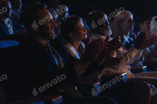 Preview: Business colleagues sitting and watching presentation with audience and clapping hands