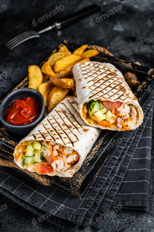 Preview: Durum doner kebab or Shawarma with meat vegetable salad and french fries. Black background. Top view