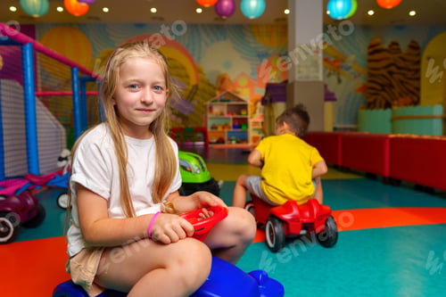 Preview: Young Girl Sitting on Toy Car in Play Room