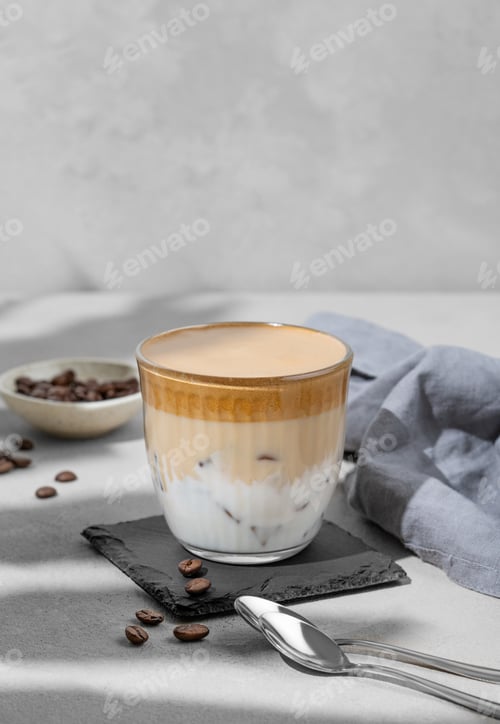 Preview: Iced dalgona coffee. Whipped instant coffee in glass with ice on a slate board on a gray background