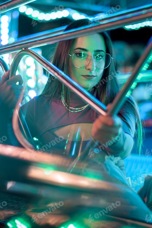Preview: Portrait of a young woman with eyeglasses illuminated by the lights of a fairground