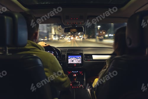 Preview: Man and woman in a car at night, view from the car.