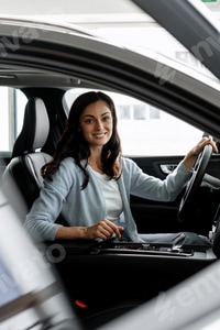 Preview: Happy businesswoman driving a modern electric car