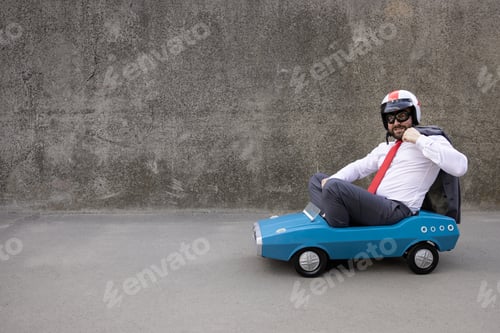 Preview: Funny businessman driving retro pedal car outdoor