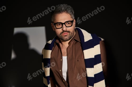 Preview: Handsome stylish man exudes elegance in a trendy studio setting with unique outfit