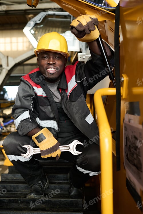 Preview: Happy young constructor of industrial machines looking at camera