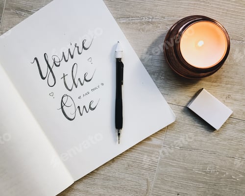 Preview: Calligraphy and scripted writing in a notebook with a mechanical pencil and candle with matches.