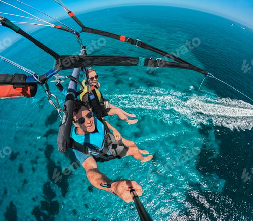 Preview: Couple enjoying parasailing over clear blue ocean waters on a sunny day