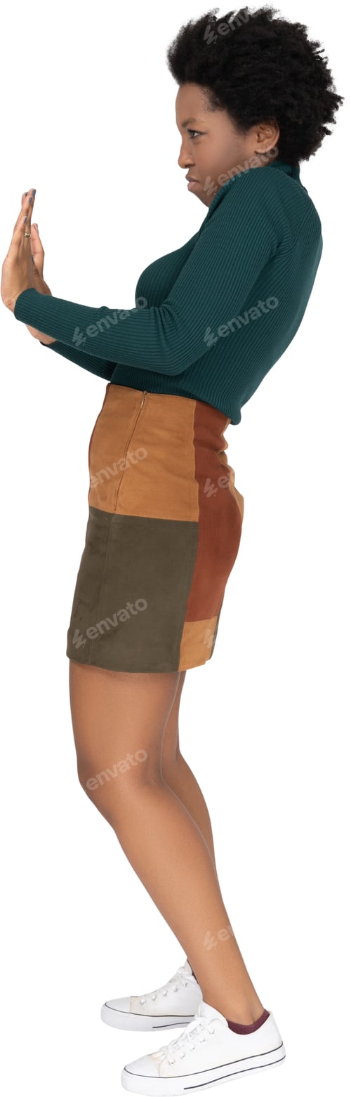 Preview: a woman in a skirt and a green sweater standing with her arms crossed