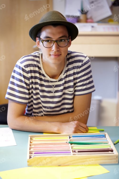 Young Man Drawing with Colored Pencils Indoors