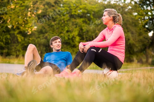Preview: Man looking at woman sitting on soccer ball at park
