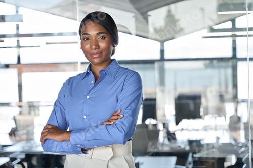 Preview: Young confident business woman executive standing in office looking at camera.