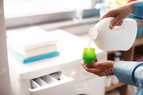 Preview: A housewife carefully doses the detergent to put in the washing machine