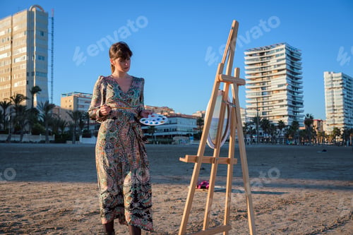 Preview: Woman Standing Next to Easel on Beach
