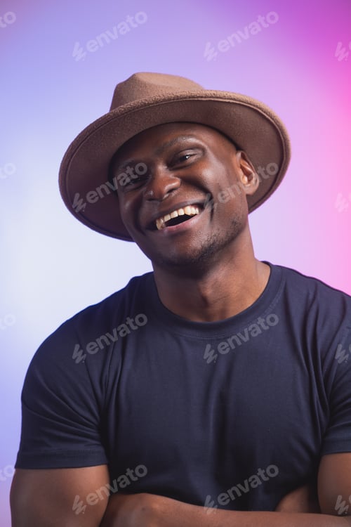 Preview: Smiling happy american african man wear stylish hat on pink and purple background. Festive and party