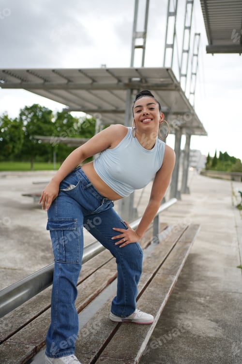 Preview: A woman in blue jeans and a tank top is posing for a picture