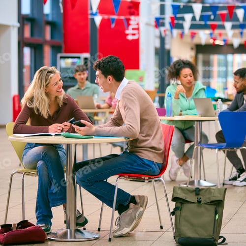 Preview: Two College Or University Students With Mobile Phone Working Together In Study Area