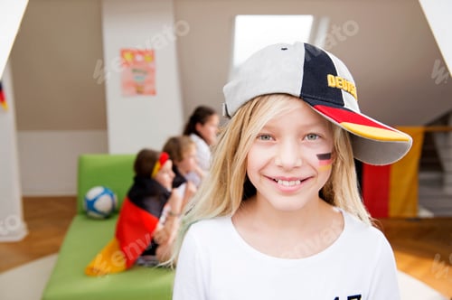 Preview: Portrait of a girl with German face paint and cap with friends in background