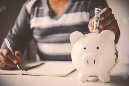 Preview: Hands are money into a piggy bank - concept of saving.