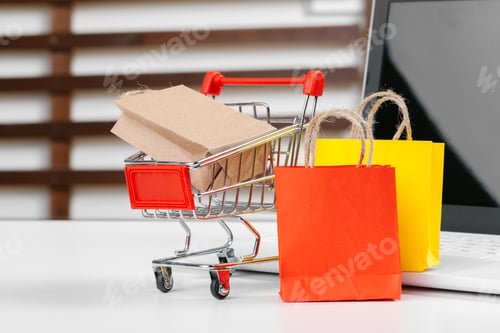 Preview: Online shopping concept. Shopping cart, laptop on the desk