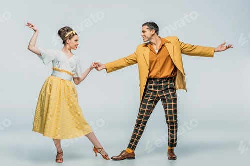 Preview: stylish dancers holding hands while dancing boogie-woogie on grey background
