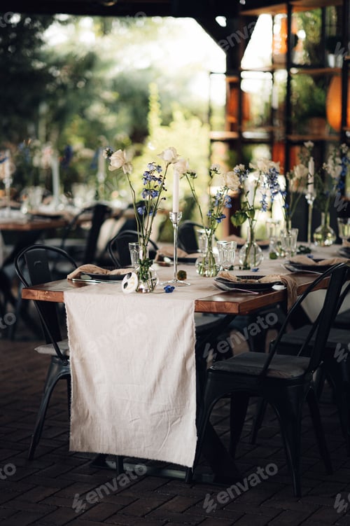 Preview: Wedding table set decorated with a selection of tall glass vases containing white flowers.