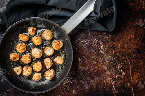 Preview: Fried scallops with butter lemon sauce in a skillet. Dark background. Top view. Copy space