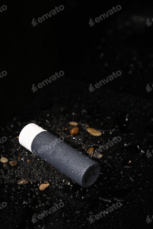 Preview: A black bottle of essential with empty label on dark background, cosmetic packaging template design
