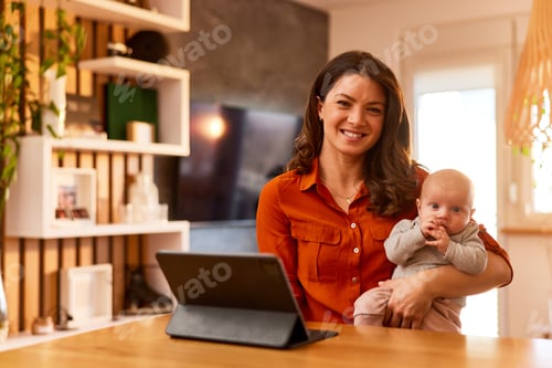 Preview: Portrait of a pretty mother and her cute little baby girl at home with a tablet on the stand.